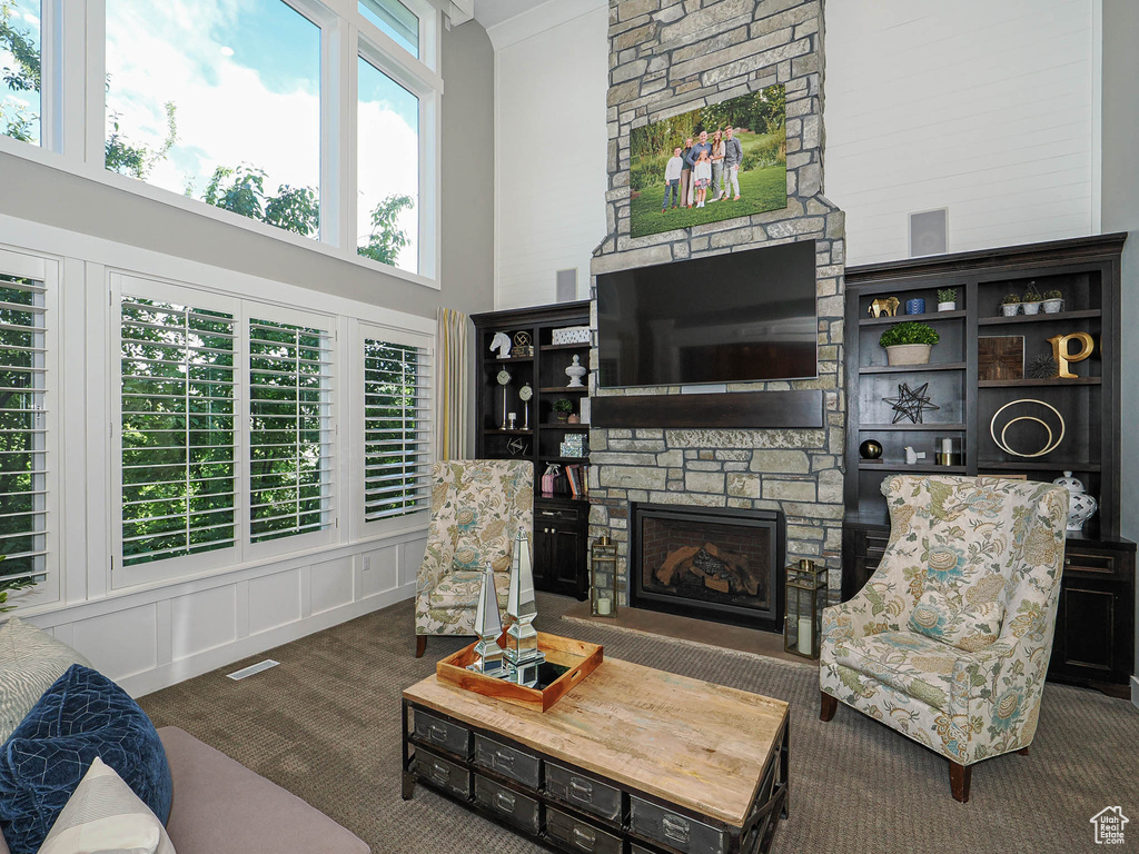 Carpeted living room with a towering ceiling and a stone fireplace