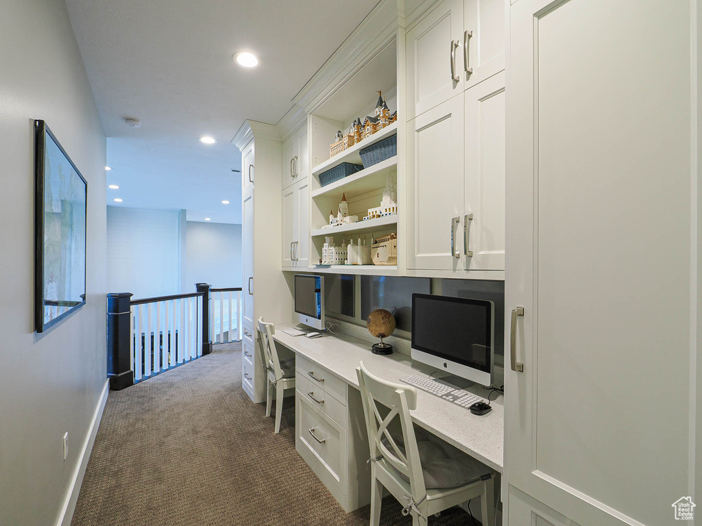 Office space featuring built in desk, dark carpet, recessed lighting, and baseboards