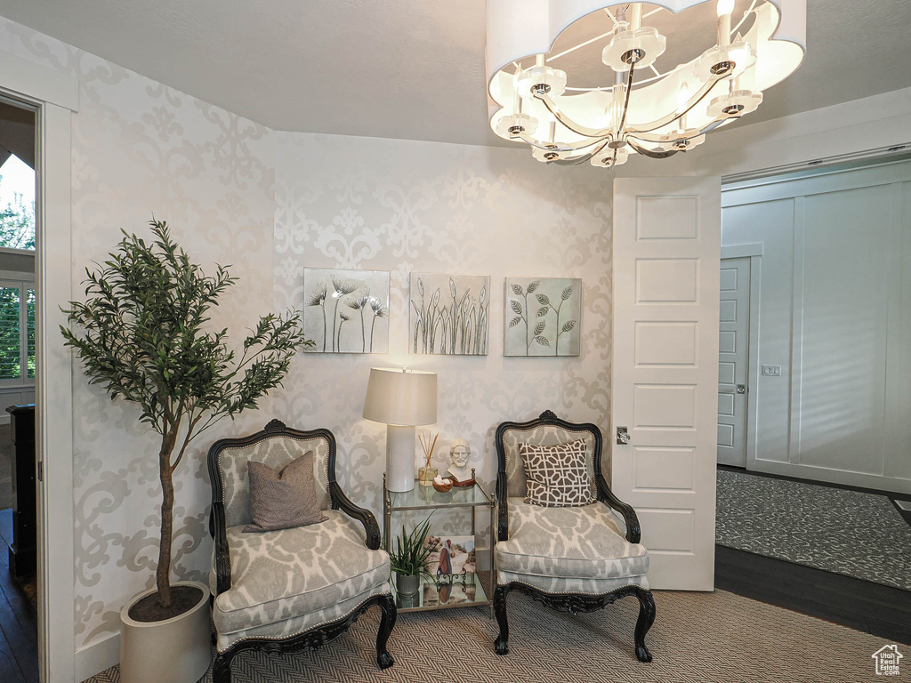 Living area with wallpapered walls, a chandelier, and wood finished floors