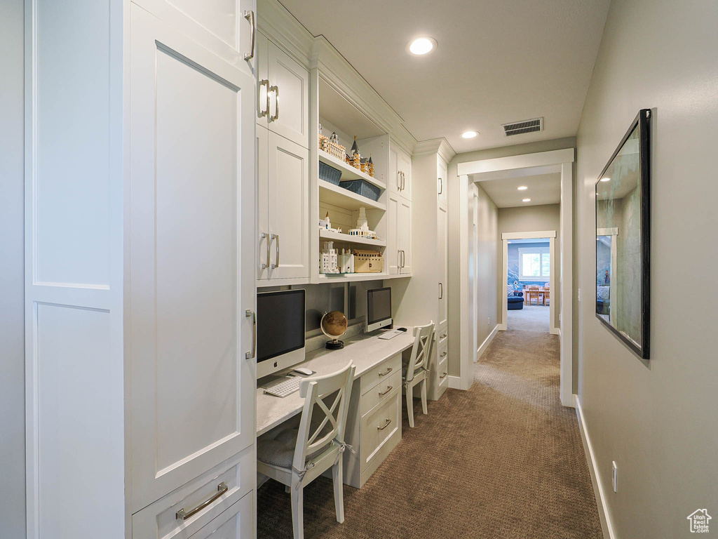 Home office with built in desk, dark colored carpet, recessed lighting, and baseboards