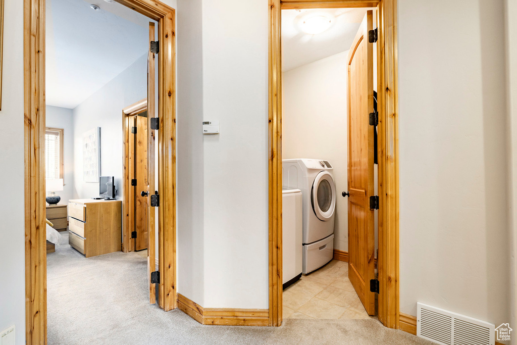 Laundry area featuring light carpet, independent washer and dryer, and baseboards