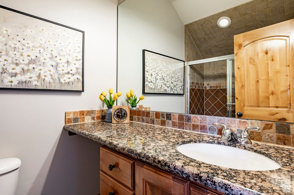 Bathroom featuring toilet, vanity, and a stall shower