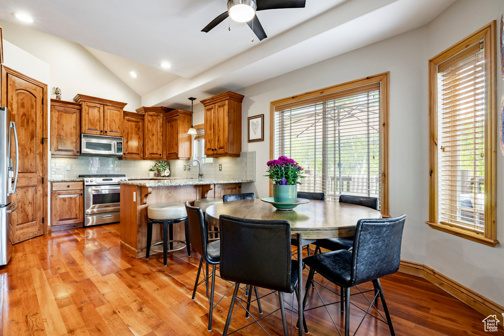 Dining space with lofted ceiling, light wood-type flooring, a ceiling fan, recessed lighting, and baseboards