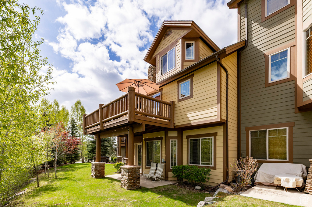 Back of house featuring a patio, a lawn, and a deck