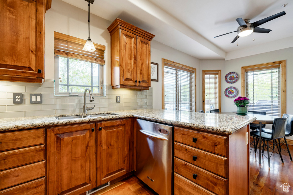 Kitchen with a sink, stainless steel dishwasher, a peninsula, wood finished floors, and plenty of natural light