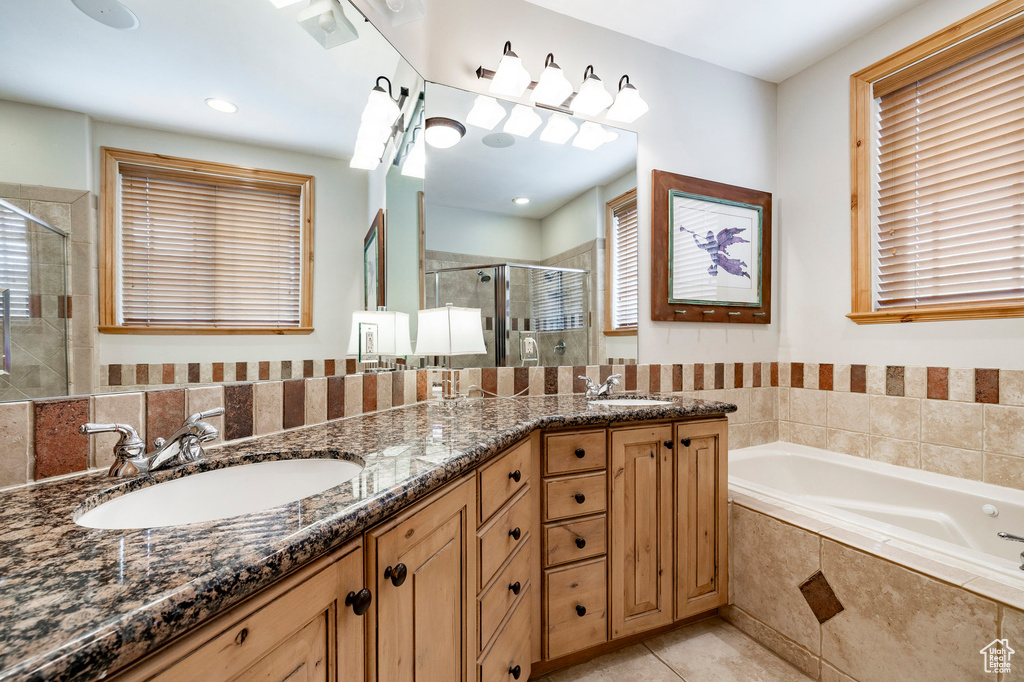Bathroom featuring a shower stall, a bath, double vanity, tile patterned floors, and plenty of natural light