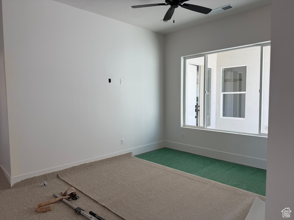 Carpeted spare room with baseboards and a ceiling fan
