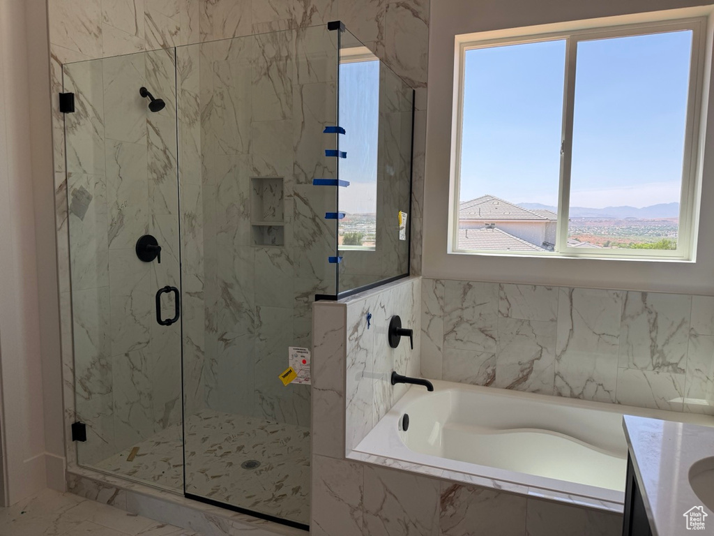 Bathroom featuring a bath, healthy amount of natural light, a marble finish shower, and marble finish floors