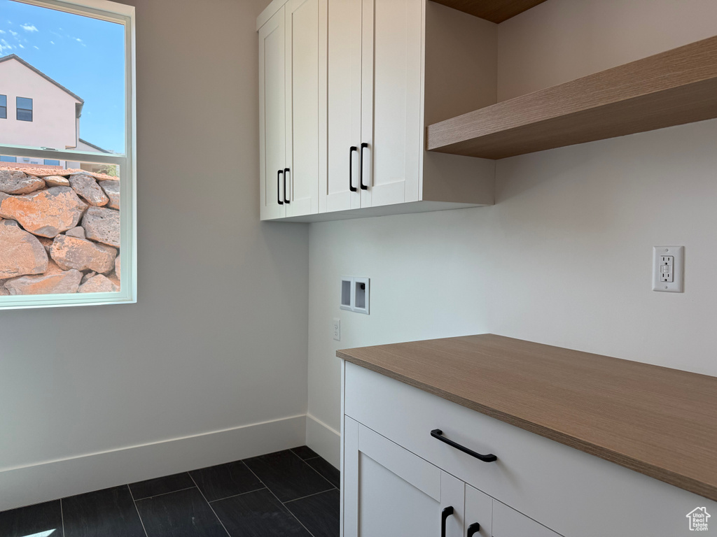 Laundry area featuring cabinet space, washer hookup, and dark tile patterned flooring