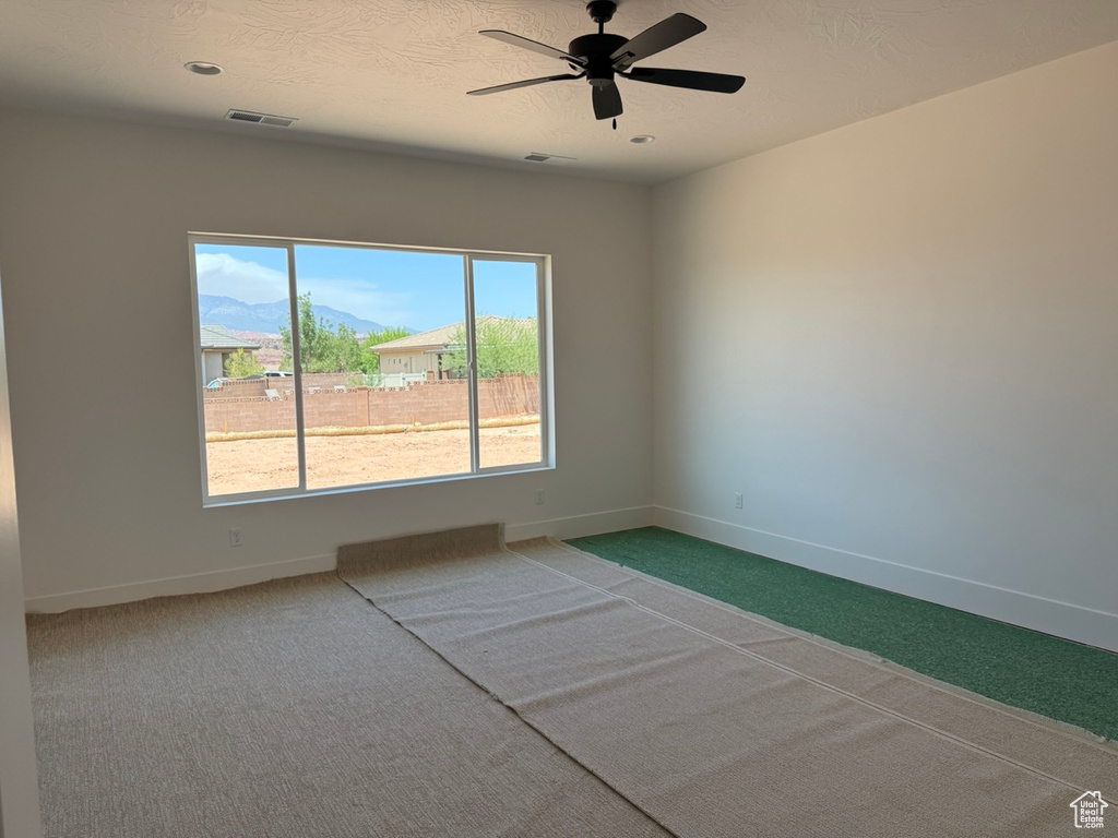 Empty room with carpet floors, a ceiling fan, and a mountain view