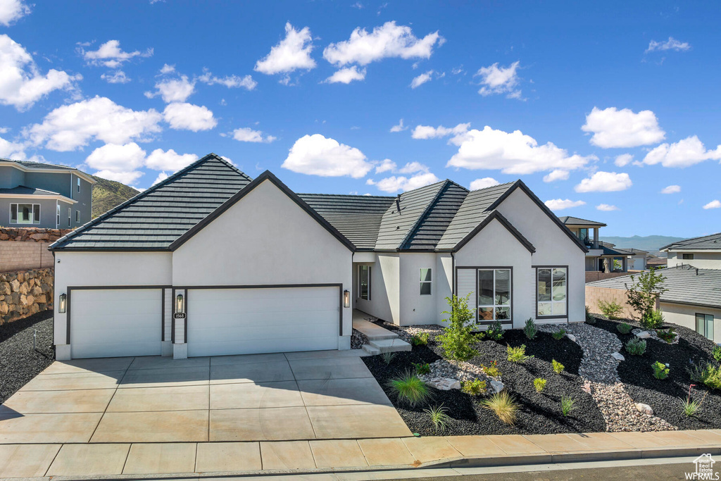 View of front of property featuring a garage, stucco siding, concrete driveway, and a tiled roof