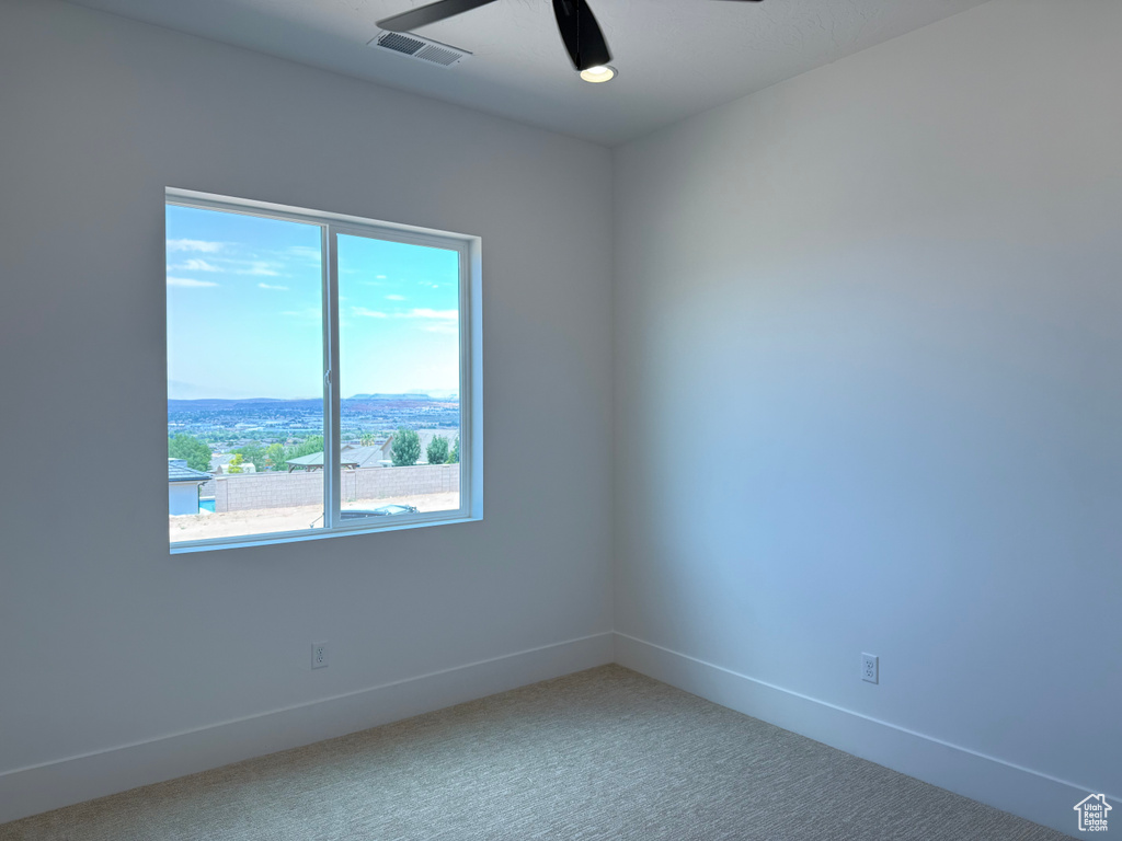 Empty room with a ceiling fan and light carpet
