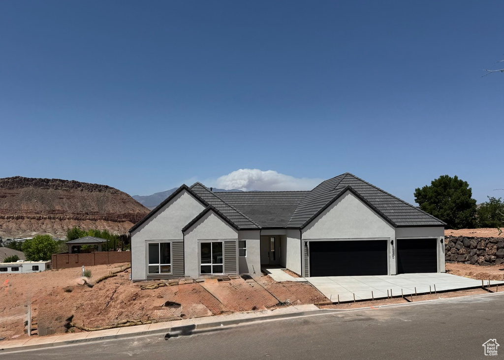View of front of home featuring an attached garage, stucco siding, a mountain view, a tiled roof, and driveway