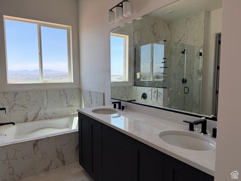 Bathroom featuring a garden tub, a marble finish shower, and double vanity