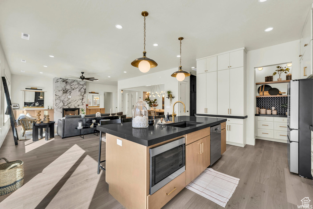 Kitchen featuring a sink, stainless steel appliances, dark countertops, ceiling fan, and a breakfast bar