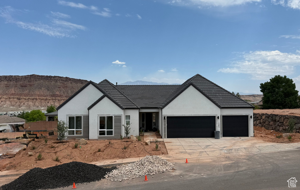 View of front of house featuring an attached garage, driveway, a mountain view, and stucco siding