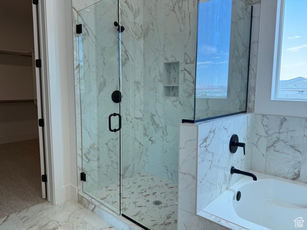 Full bathroom featuring a marble finish shower, a garden tub, a walk in closet, and marble look tile flooring