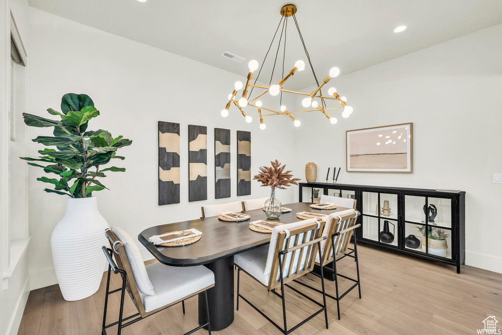 Dining area featuring light wood finished floors, a chandelier, baseboards, vaulted ceiling, and recessed lighting