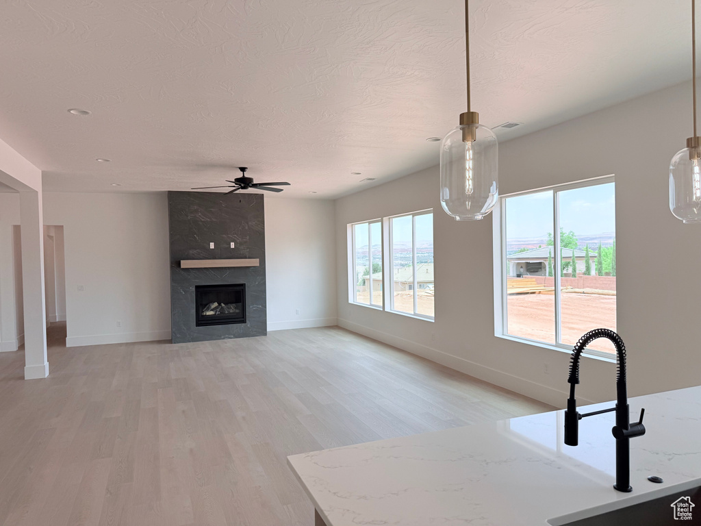 Unfurnished living room featuring a ceiling fan, light wood-type flooring, and a fireplace