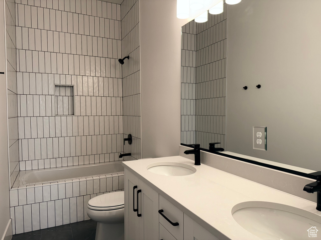 Full bathroom featuring double vanity, tiled shower / bath combo, and tile patterned floors