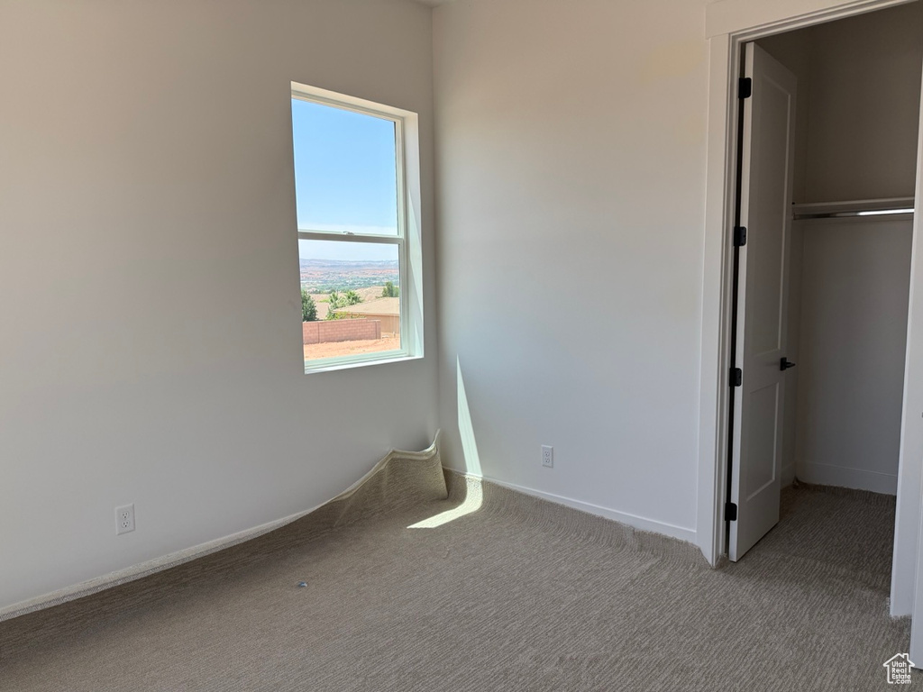Unfurnished bedroom with carpet, a closet, and a walk in closet