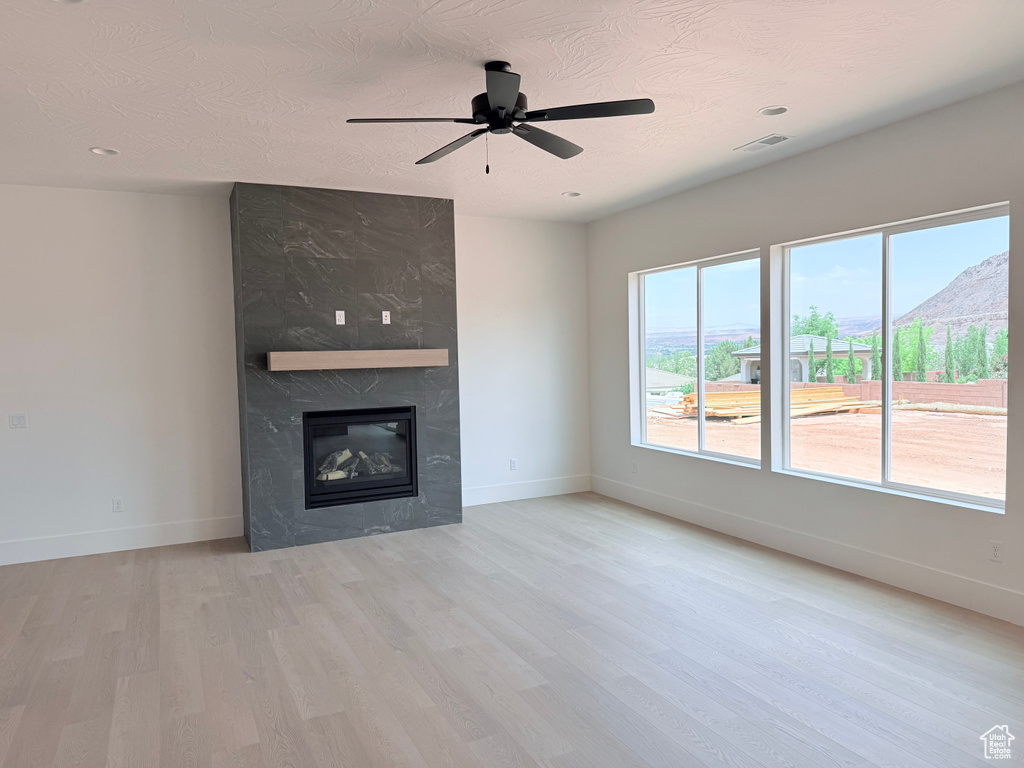 Unfurnished living room featuring wood finished floors, a ceiling fan, a fireplace, and recessed lighting