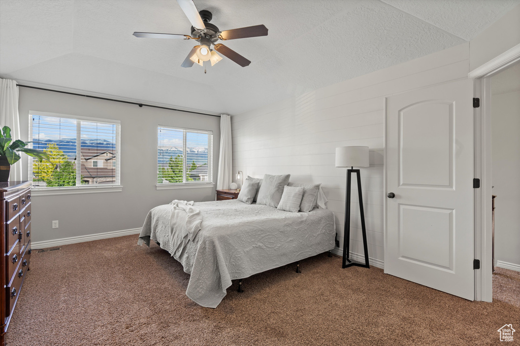 Carpeted bedroom featuring lofted ceiling, baseboards, and ceiling fan