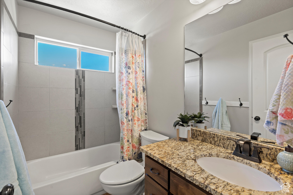 Bathroom with vanity, shower / bath combo, and toilet