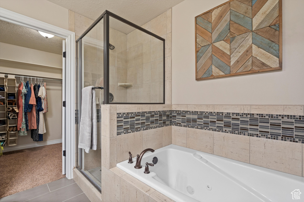 Bathroom with a stall shower, a whirlpool tub, a walk in closet, tile patterned floors, and a textured ceiling