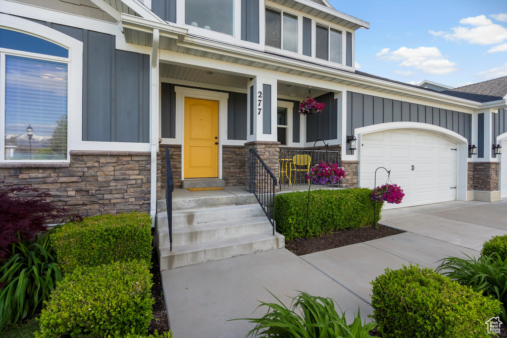 Entrance to property with stone siding, board and batten siding, driveway, and a porch