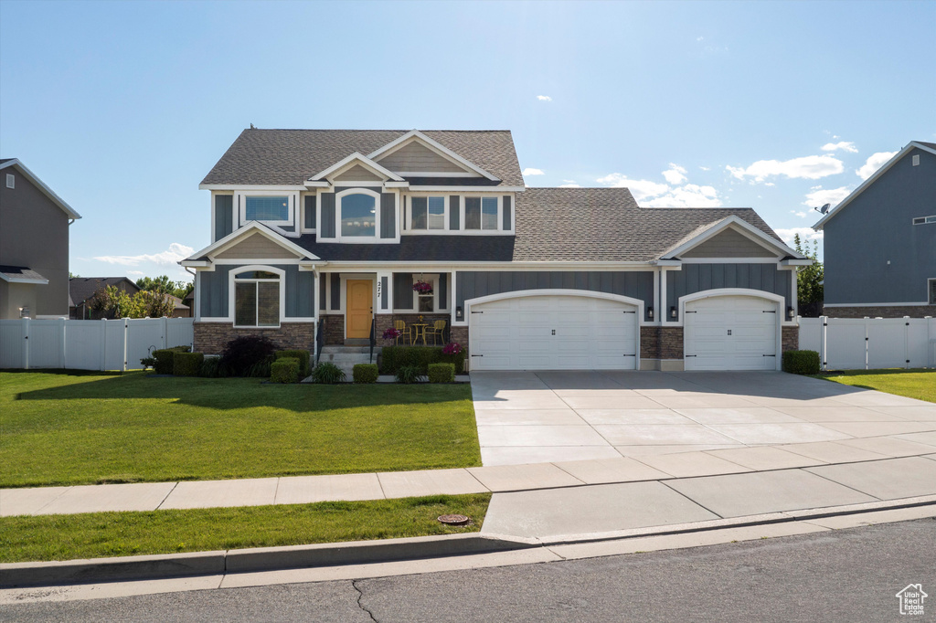Craftsman-style house with a garage, roof with shingles, concrete driveway, stone siding, and a gate