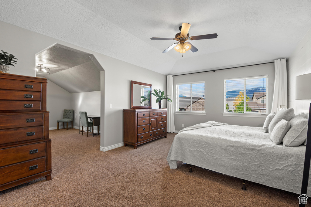 Bedroom with lofted ceiling, light carpet, a textured ceiling, baseboards, and ceiling fan