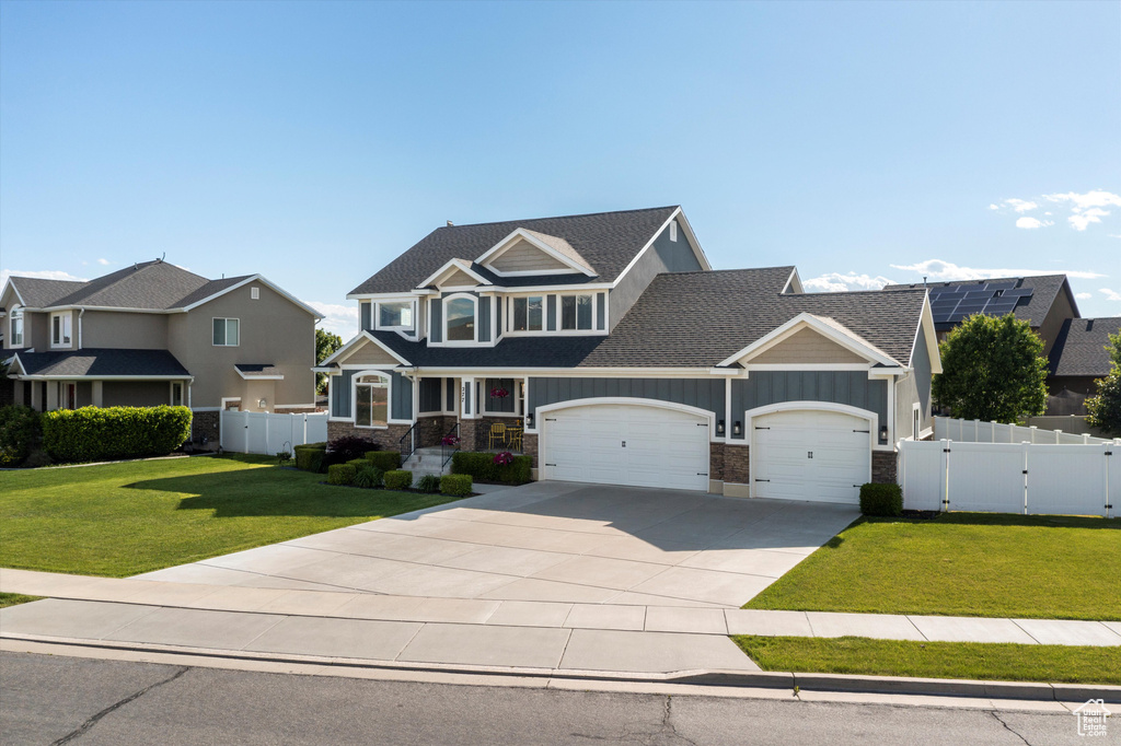 Craftsman house featuring an attached garage, driveway, a gate, stone siding, and a shingled roof