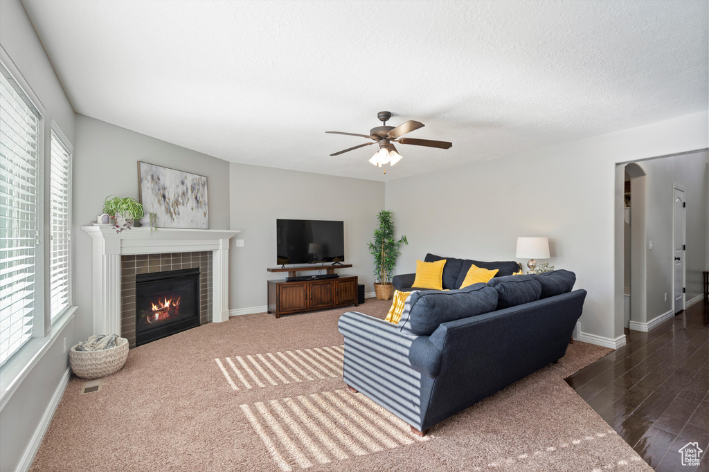 Living area with a tile fireplace, ceiling fan, baseboards, and wood finished floors