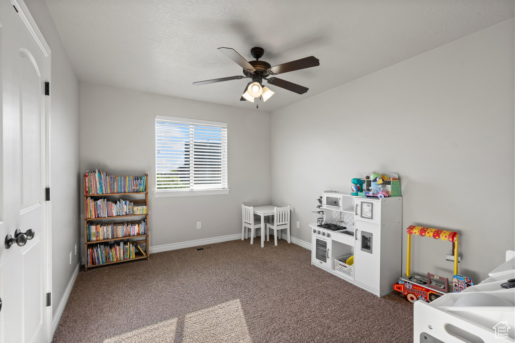 Recreation room with ceiling fan, carpet floors, and baseboards