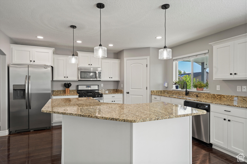 Kitchen with stainless steel appliances, dark wood finished floors, a kitchen island, recessed lighting, and a sink