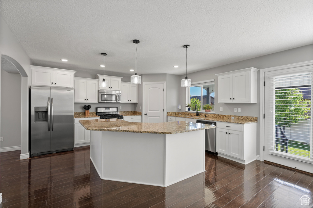 Kitchen with stainless steel appliances, recessed lighting, white cabinetry, a center island, and dark wood-type flooring