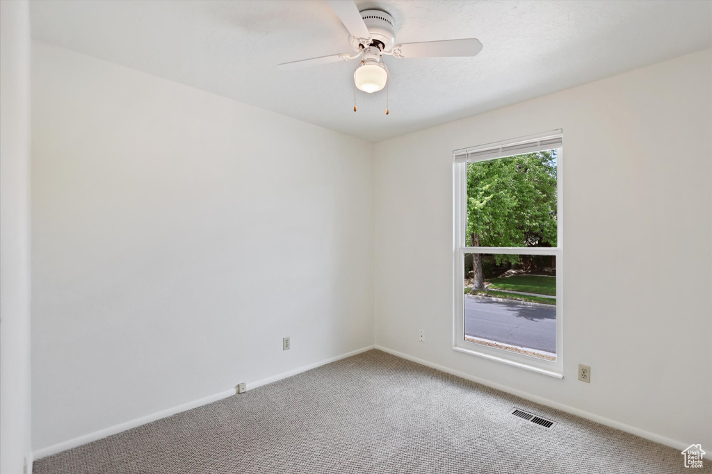 Carpeted empty room featuring baseboards and ceiling fan