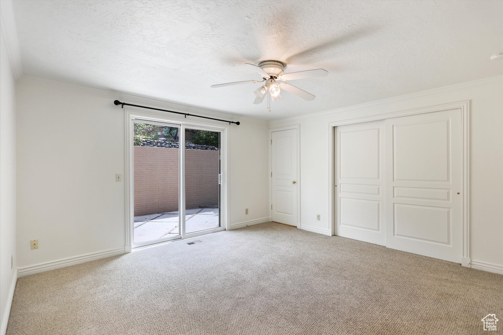 Unfurnished bedroom featuring access to outside, carpet flooring, a textured ceiling, a closet, and baseboards