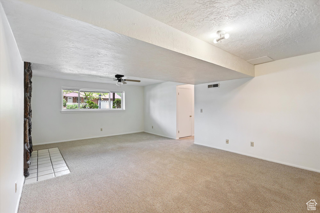 Unfurnished room featuring light carpet, a textured ceiling, ceiling fan, and baseboards