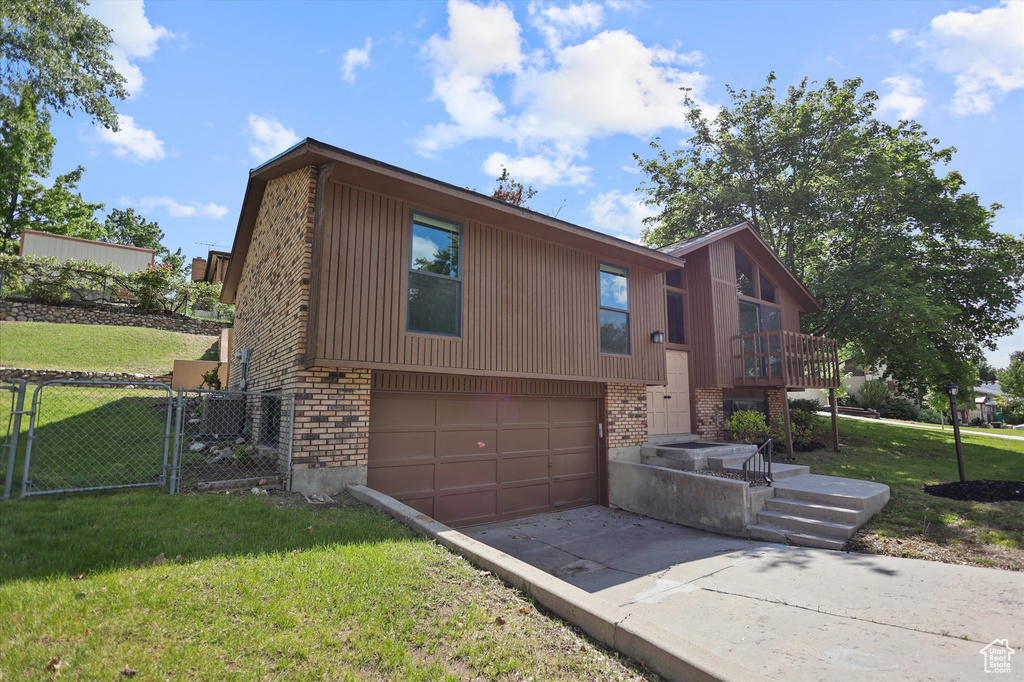 View of front of property featuring a garage, concrete driveway, brick siding, and a gate