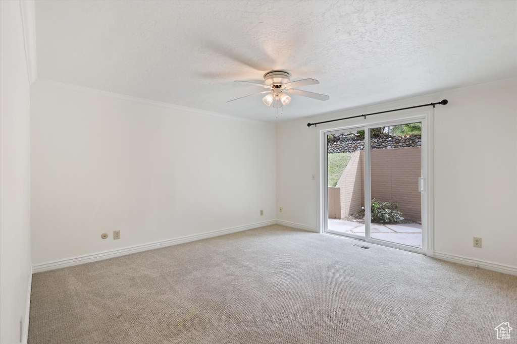 Unfurnished room featuring ceiling fan, carpet flooring, baseboards, a textured ceiling, and ornamental molding