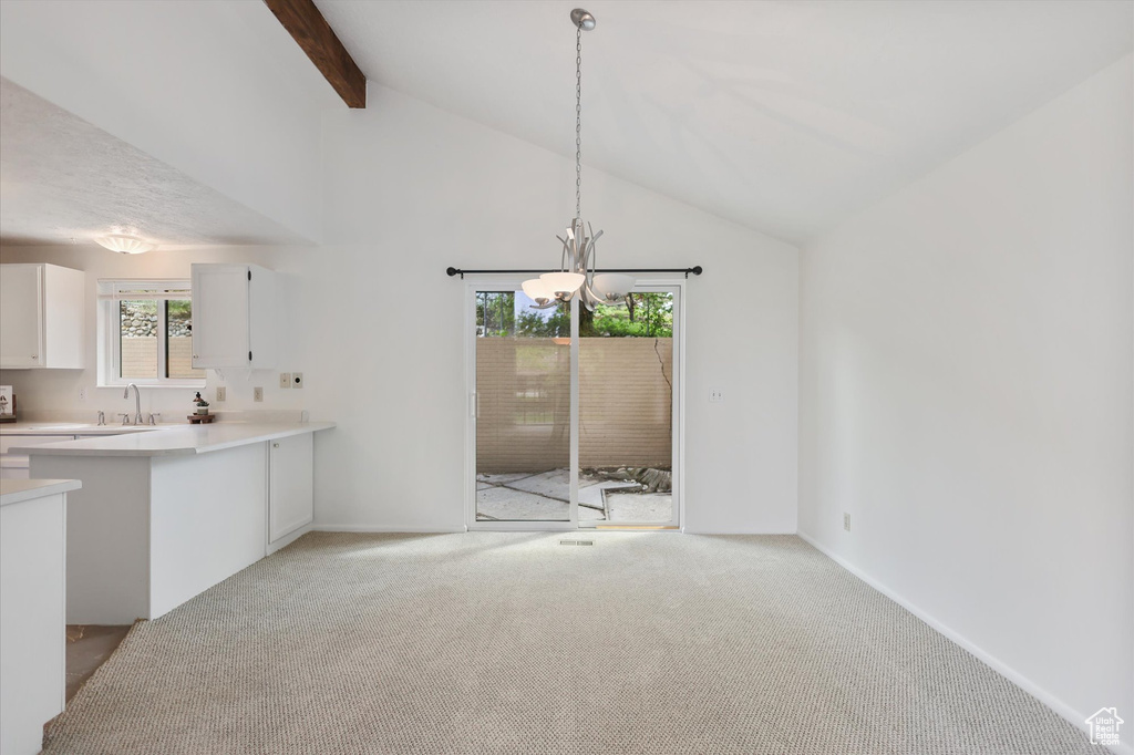 Kitchen with a chandelier, white cabinets, light colored carpet, light countertops, and beam ceiling
