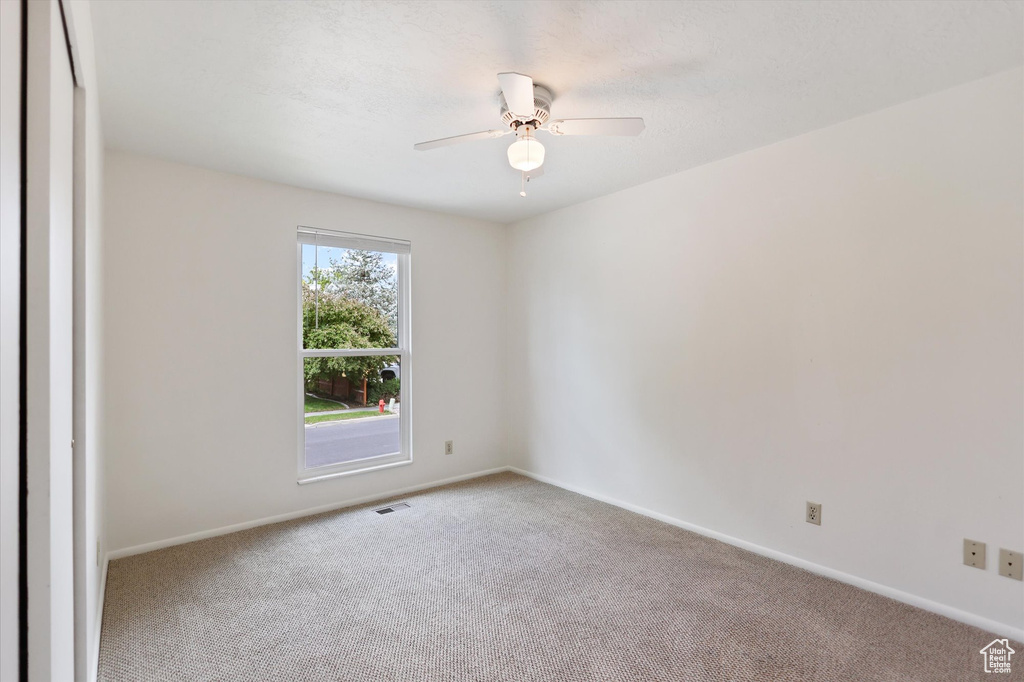 Carpeted empty room featuring a ceiling fan and baseboards