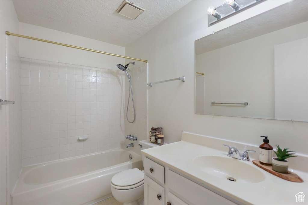 Bathroom featuring toilet, a textured ceiling, vanity, and shower / bathtub combination
