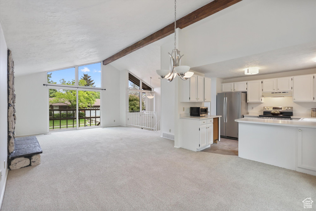 Kitchen with appliances with stainless steel finishes, open floor plan, light colored carpet, light countertops, and white cabinets
