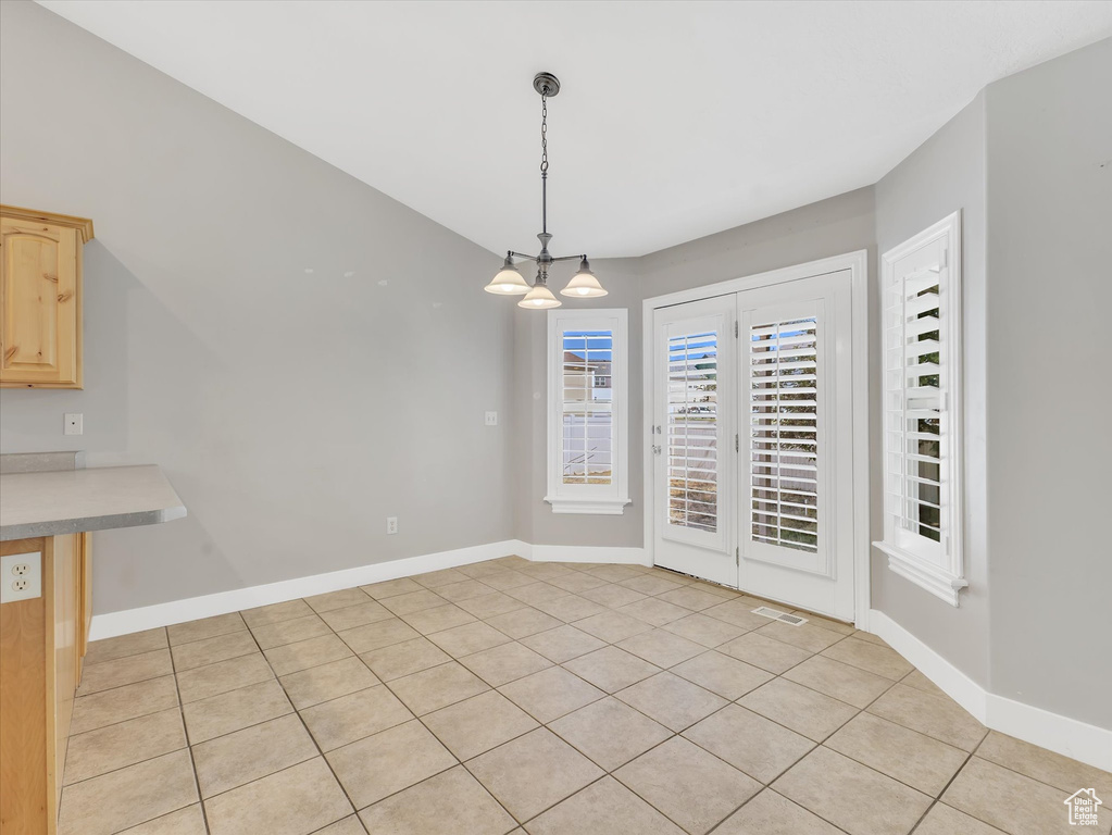 Unfurnished dining area with light tile patterned floors and baseboards