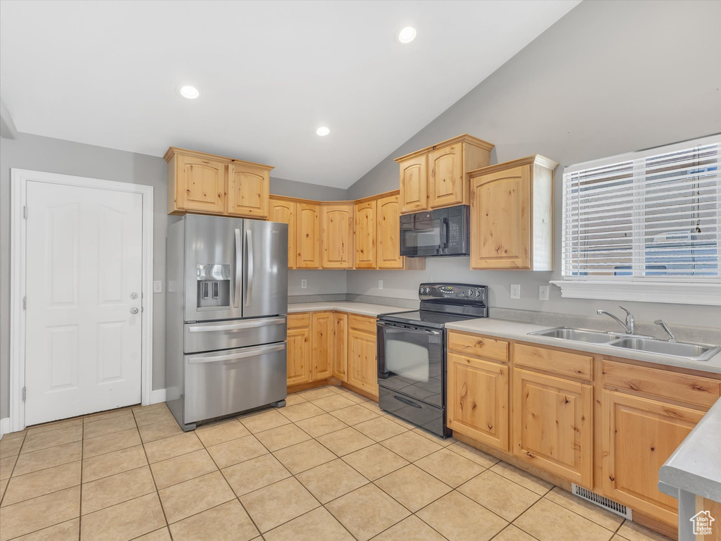 Kitchen featuring black appliances, a sink, light brown cabinetry, vaulted ceiling, and light countertops