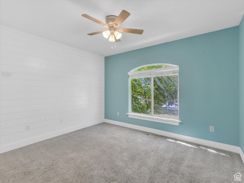 Carpeted empty room featuring a ceiling fan and baseboards