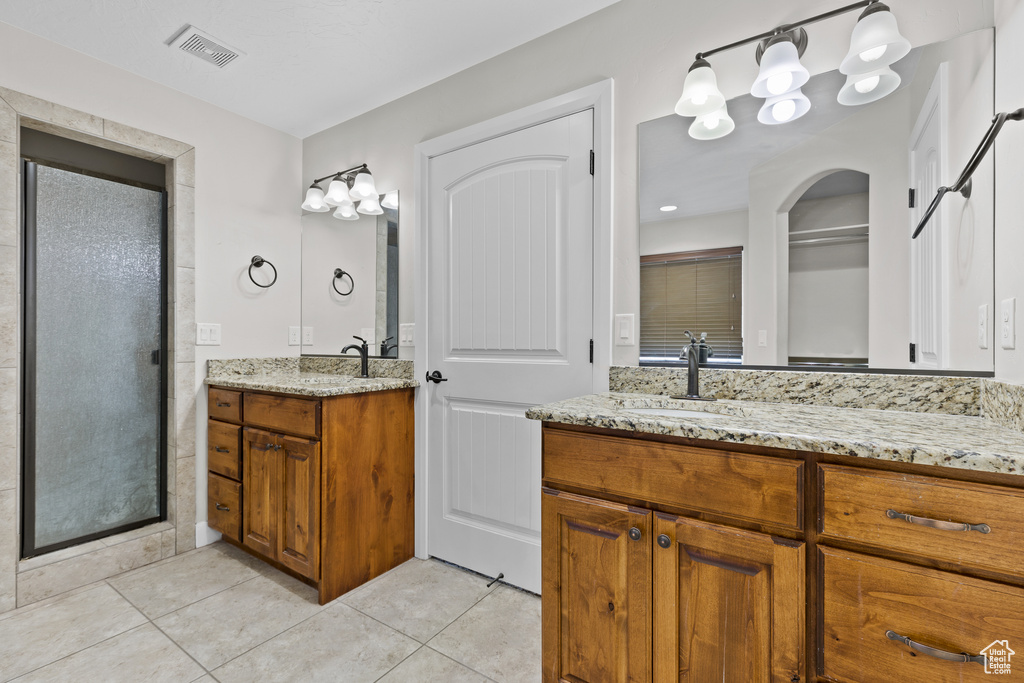 Bathroom featuring tile patterned flooring, a shower stall, and two vanities